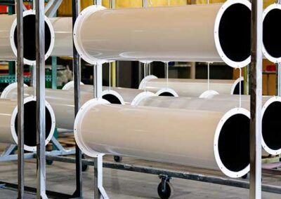 Large powder coated pipes hanging to dry on racks in a warehouse.