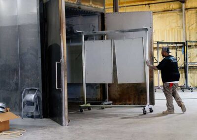Tech pushing powder coated items into a storage area.