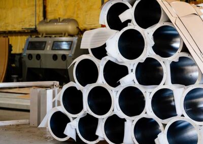 Stack-of-powder-coated-pipes preparing to deliver - machinery in the background.