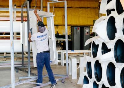 Tech wearing logo t-shirt taking down a piece from the hanging racks with white metal pipes being prepared to deliver.