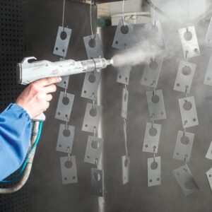 powder coating spray being applied to small metal pieces