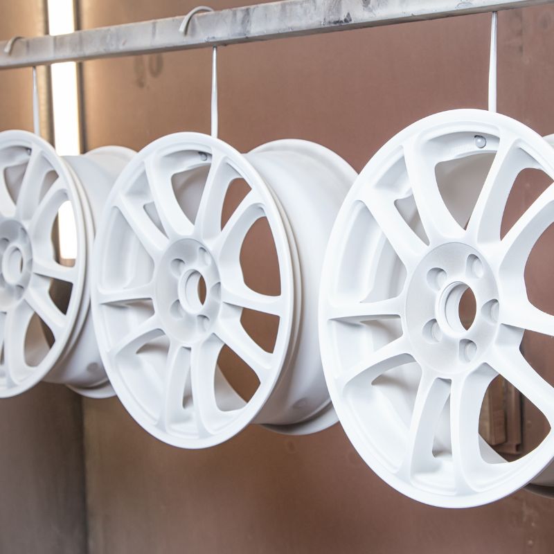 freshly painted white vehicle rims hanging to dry